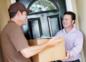 Man receiving a package delivery from a courier at his home.